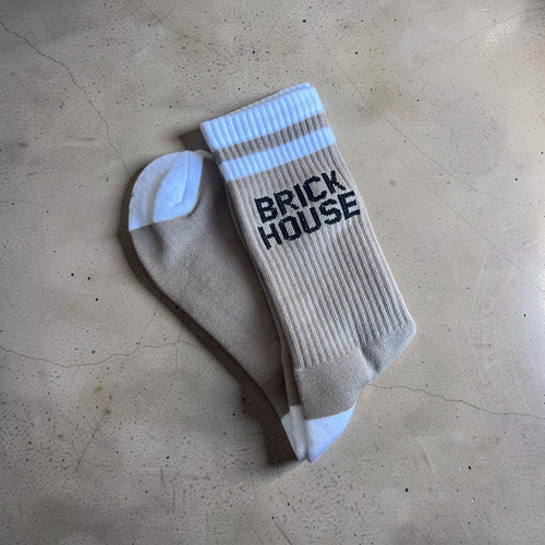 Beige sock with 'BRICK HOUSE' text on a beige surface