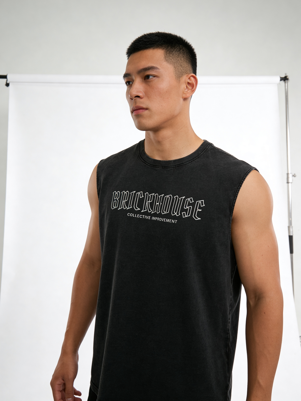 Man wearing a black sleeveless shirt with 'BRICKHOUSE' branding against a white background